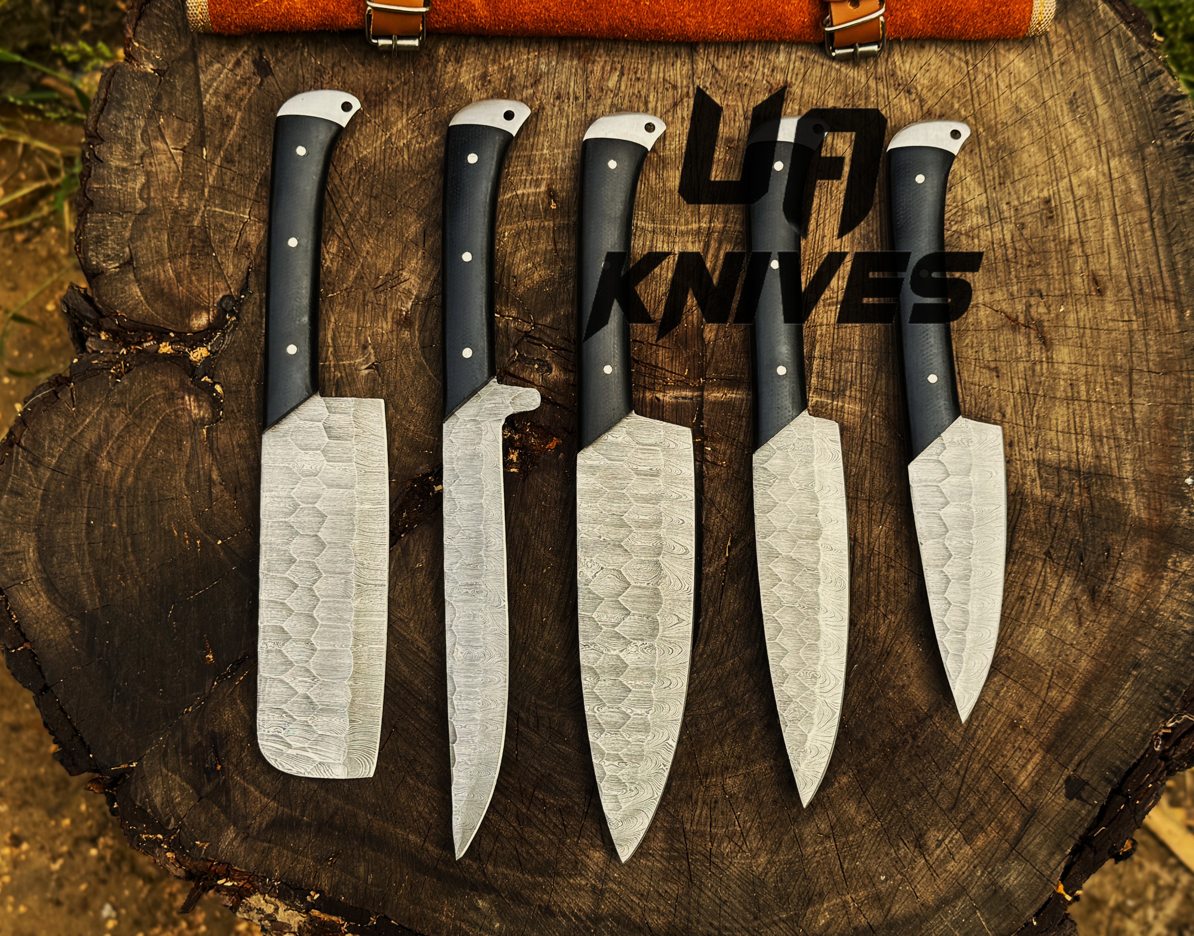 UA Knives Midnight Forge handmade Damascus steel 5-piece BBQ chef set with genuine leather bag displayed on a countertop.