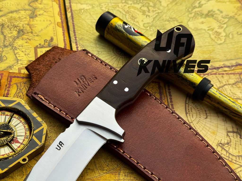 UA Knives Bear Claw hunting knife with hand-forged blade and G10 Micarta handle, displayed on a wooden surface.