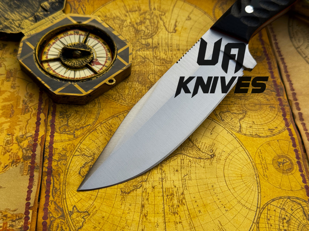 UA Night Stalker hunting knife with 12C27 stainless steel blade and black handle, displayed on a wooden surface.