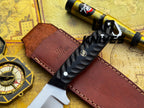 UA Night Stalker hunting knife with 12C27 stainless steel blade and black handle, displayed on a wooden surface.