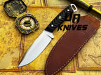 UA Night Stalker hunting knife with 12C27 stainless steel blade and black handle, displayed on a wooden surface.